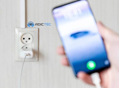 ¿Es Necesario Desenchufar el Cargador cuando no se está Cargando Nada? 13 Un cargador de teléfono conectado a una toma de corriente, con un teléfono móvil desenfocado en primer plano.