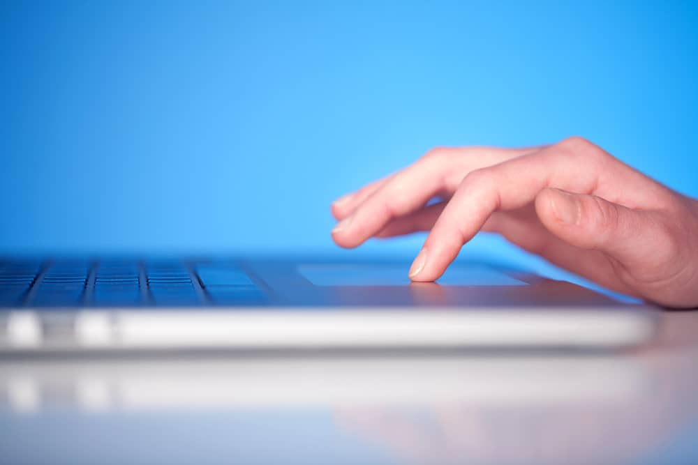 ¿Por qué no funciona el touchpad de mi laptop y qué puedo hacer? 7 Una mano sobre el touchpad de un portátil, ilustrando un problema con el dispositivo.