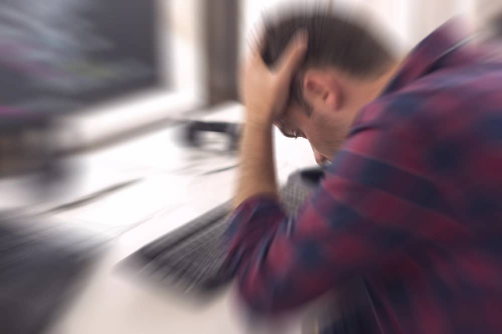 Cómo deshacerte del zumbido, ruido y vibraciones en tu PC 4 Imagen borrosa de una persona frustrada frente a un ordenador, que sugiere un mi PC hace un zumbido, problema técnico